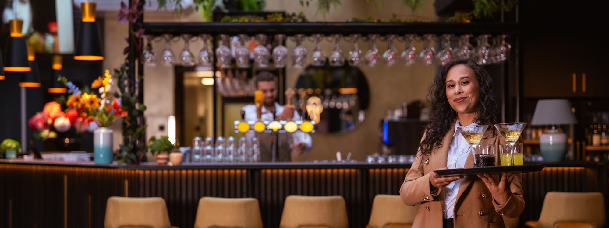 Vrouw met dienblad staat voor bar